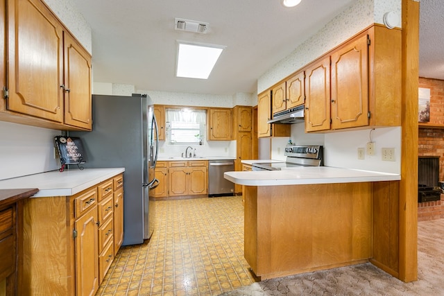 3305 Sierra Ct, San Angelo, TX 76904 - kitchen with under cabinet range hood, stainless steel appliances, a peninsula, a sink, and brown cabinetry