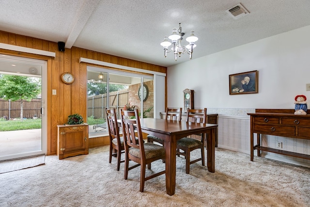 3305 Sierra Ct, San Angelo, TX 76904 - carpeted dining space with a chandelier, plenty of natural light, a textured ceiling, wood walls, and wainscoting