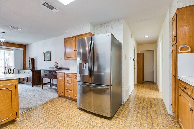 3305 Sierra Ct, San Angelo, TX 76904 - kitchen with stainless steel fridge with ice dispenser, light countertops, brown cabinetry, light colored carpet, and recessed lighting