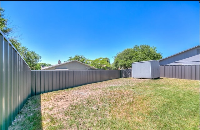 view of yard with a fenced backyard, an outdoor structure, and a storage unit