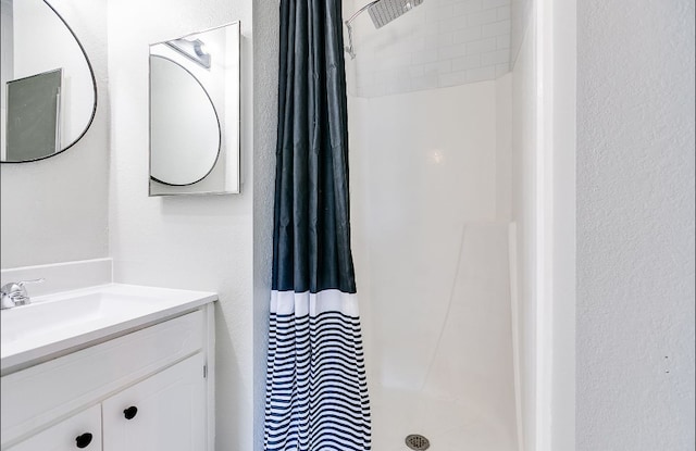 full bathroom with a textured wall, vanity, and curtained shower