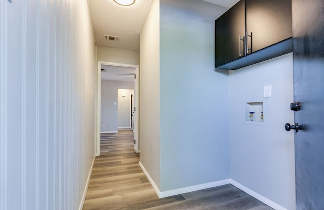 clothes washing area featuring visible vents, baseboards, hookup for a washing machine, wood finished floors, and cabinet space