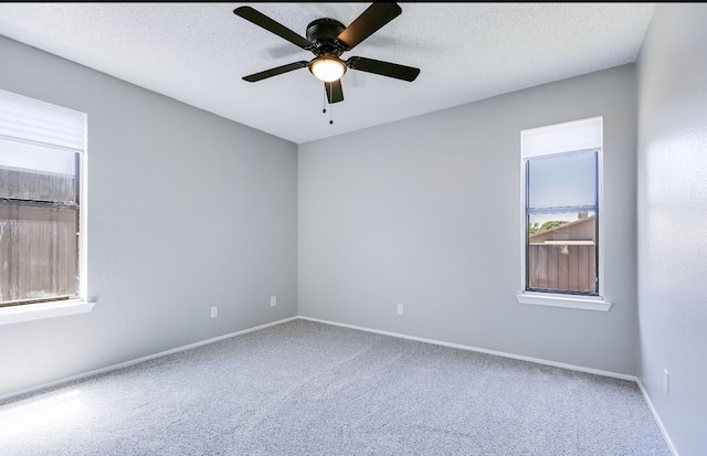 carpeted empty room with a ceiling fan, baseboards, and a wealth of natural light
