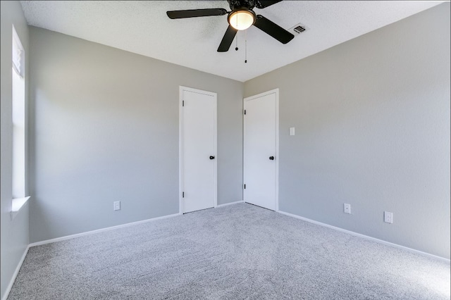 carpeted empty room featuring baseboards, a ceiling fan, and visible vents