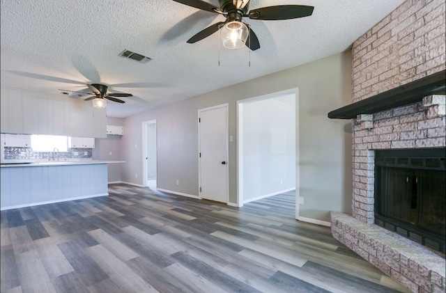 unfurnished living room featuring dark wood-type flooring, a textured ceiling, visible vents, and ceiling fan