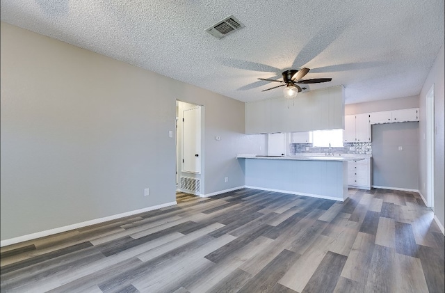 kitchen featuring a peninsula, dark wood finished floors, visible vents, white cabinetry, and ceiling fan