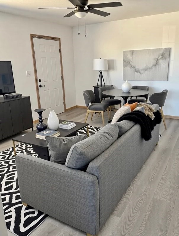 living area with ceiling fan, baseboards, and light wood-style floors