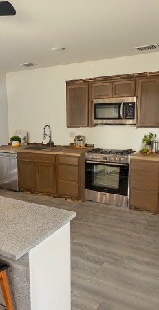 kitchen featuring visible vents, light countertops, light wood-style floors, stainless steel appliances, and a sink