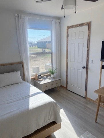 bedroom with light wood-type flooring, baseboards, and ceiling fan