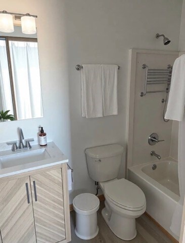 full bath with tub / shower combination, toilet, vanity, and wood finished floors