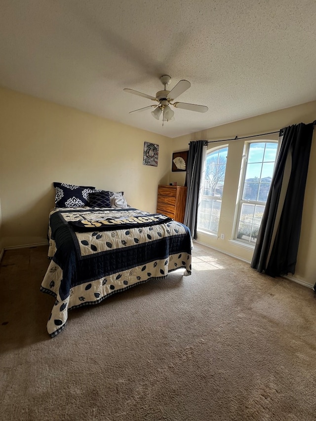 bedroom featuring light carpet, ceiling fan, and a textured ceiling