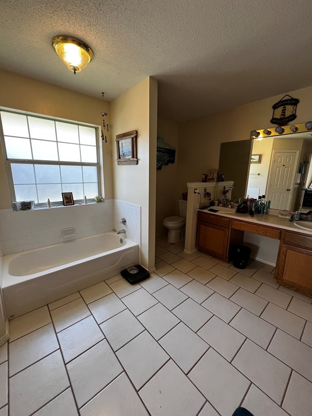 bathroom with tile patterned flooring, vanity, toilet, a bath, and a textured ceiling