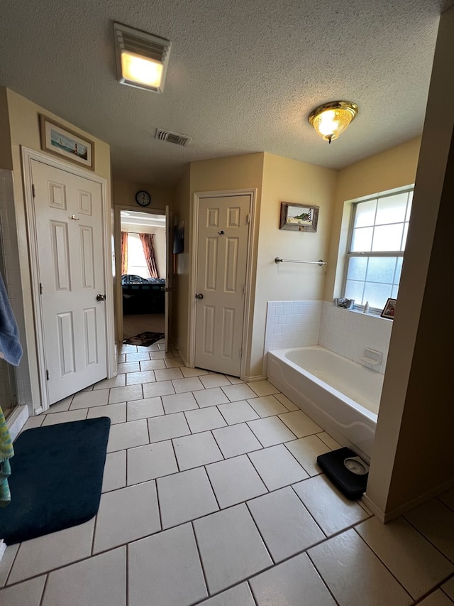 bathroom featuring tile patterned floors, a textured ceiling, and a bathtub