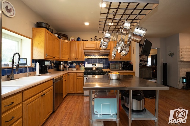 kitchen featuring sink, light wood-type flooring, stainless steel range with gas cooktop, dishwasher, and backsplash