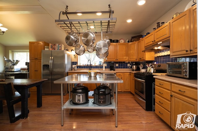 kitchen featuring appliances with stainless steel finishes, a center island, light hardwood / wood-style flooring, and decorative backsplash