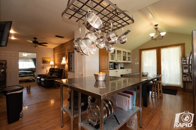 kitchen featuring a kitchen bar, dark wood-type flooring, vaulted ceiling, and ceiling fan with notable chandelier