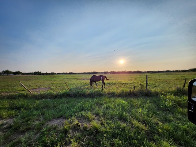 yard at dusk featuring a rural view