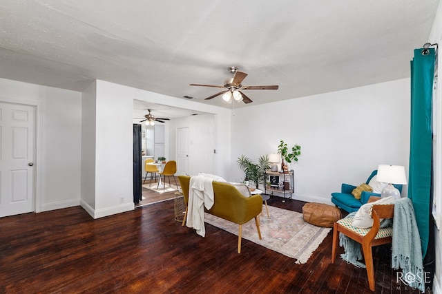 living room with a textured ceiling, dark wood-type flooring, and ceiling fan