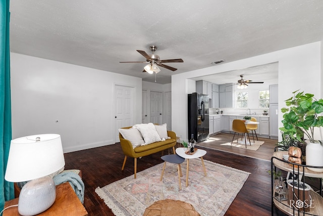 living room with sink, dark wood-type flooring, a textured ceiling, and ceiling fan