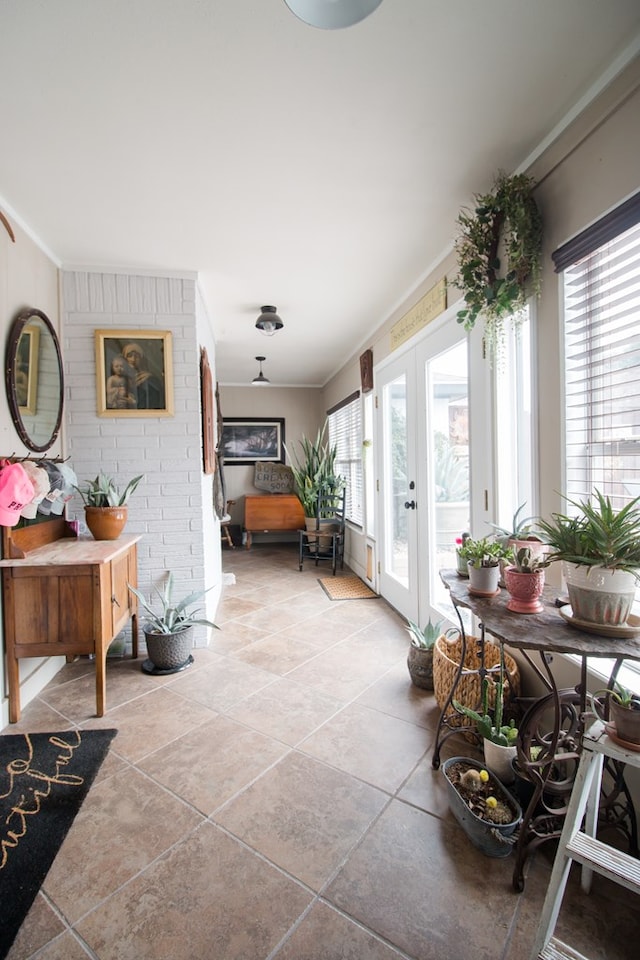 hallway with a healthy amount of sunlight, light tile patterned floors, crown molding, and french doors