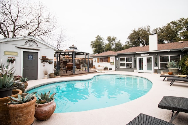 view of swimming pool with a fenced in pool, an outbuilding, a gazebo, and a storage structure