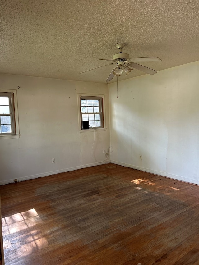 spare room with baseboards, wood finished floors, and a textured ceiling