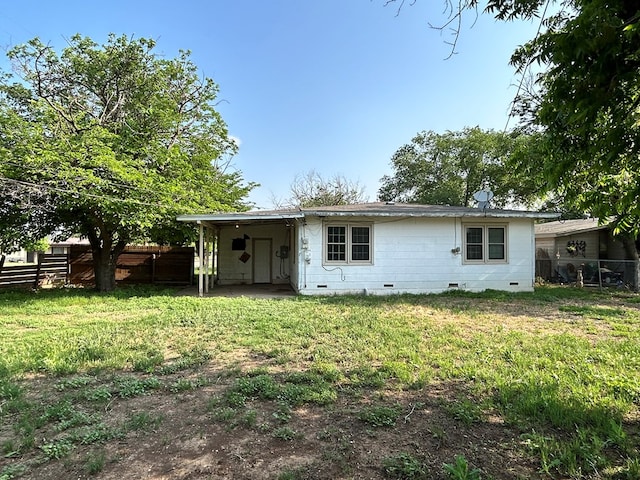 rear view of property featuring a lawn, crawl space, and a fenced backyard