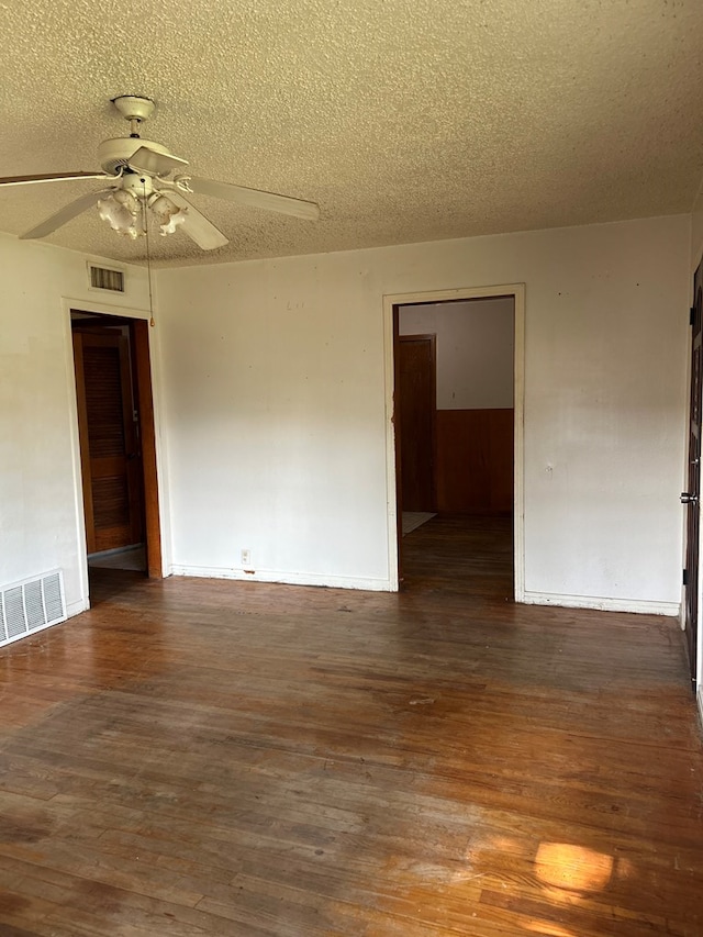 empty room featuring a textured ceiling, visible vents, wood finished floors, and a ceiling fan