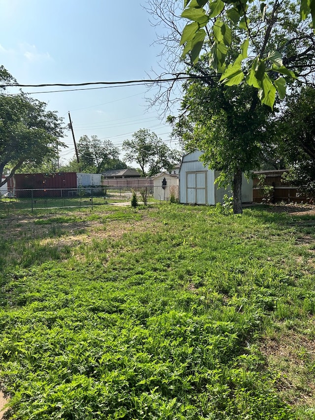 view of yard featuring an outdoor structure, a storage unit, and fence