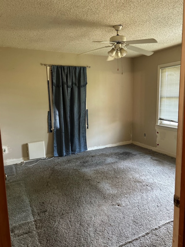 carpeted spare room with a textured ceiling, ceiling fan, and baseboards