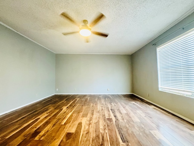 empty room with ceiling fan, a textured ceiling, wood finished floors, and baseboards