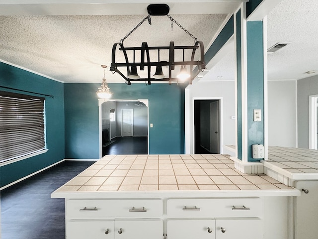 kitchen featuring dark wood-style flooring, tile counters, visible vents, white cabinetry, and a textured ceiling