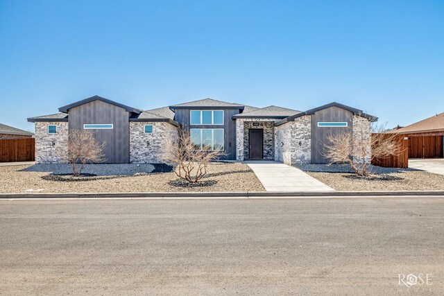 view of front of home featuring stone siding and fence