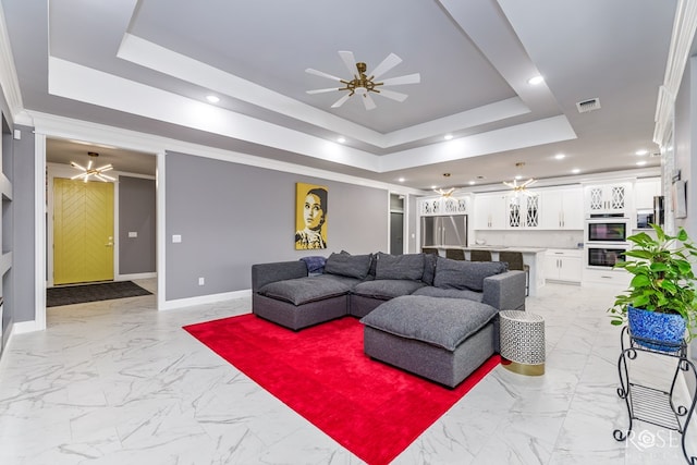 living room featuring ceiling fan, a raised ceiling, visible vents, and baseboards