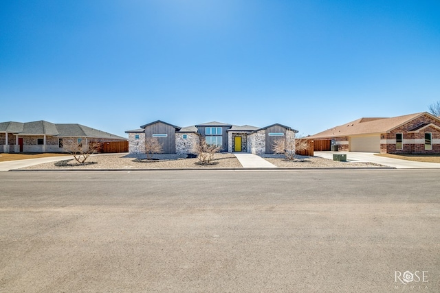 view of front of property featuring concrete driveway, board and batten siding, fence, and a residential view