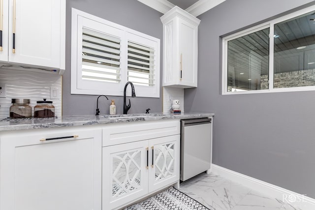 kitchen with marble finish floor, stainless steel dishwasher, white cabinets, a sink, and baseboards