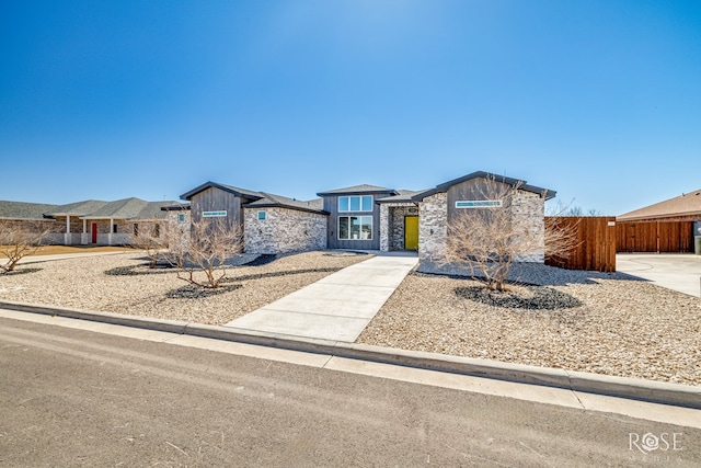 view of front of house featuring stone siding and fence