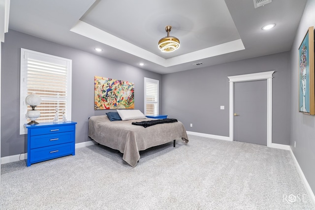 bedroom with a tray ceiling, carpet, and baseboards