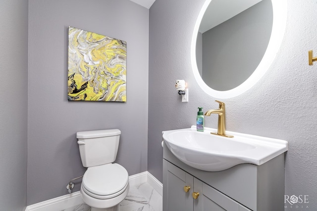 half bathroom with baseboards, a textured wall, toilet, marble finish floor, and vanity