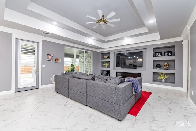 living area featuring built in features, a raised ceiling, plenty of natural light, and baseboards