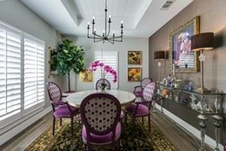 dining area featuring wood-type flooring, an inviting chandelier, and a tray ceiling