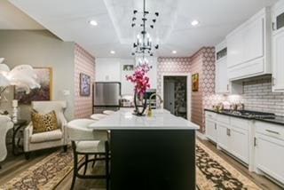 kitchen featuring white cabinetry, a kitchen breakfast bar, pendant lighting, a kitchen island with sink, and backsplash