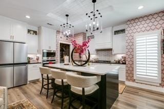 kitchen with pendant lighting, white cabinetry, a breakfast bar, and appliances with stainless steel finishes