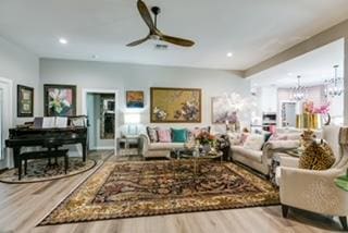 living room featuring ceiling fan with notable chandelier and hardwood / wood-style floors