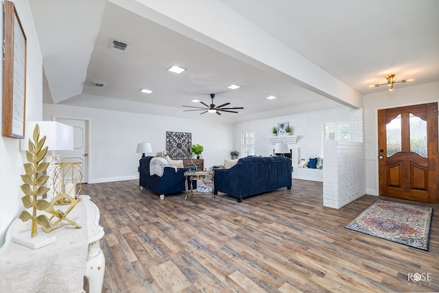 living room with ceiling fan, brick wall, a fireplace, and hardwood / wood-style floors