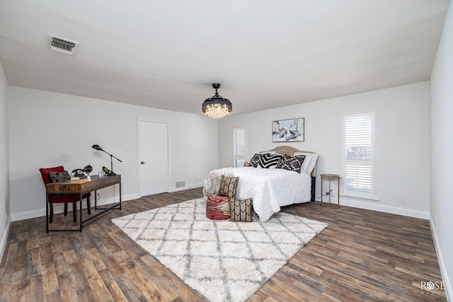 bedroom featuring an inviting chandelier and dark hardwood / wood-style flooring