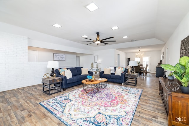 living room featuring ceiling fan with notable chandelier and hardwood / wood-style floors