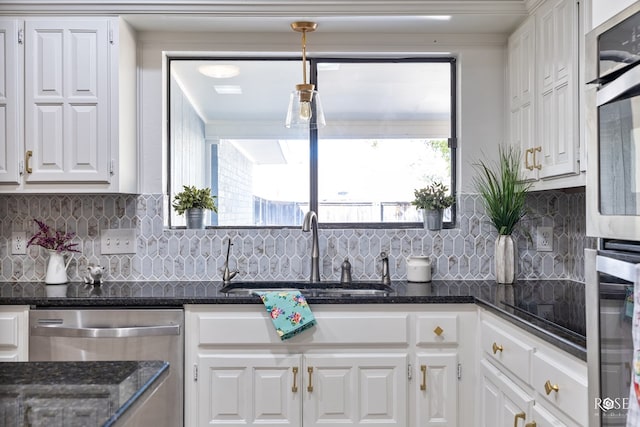 kitchen featuring appliances with stainless steel finishes, white cabinetry, sink, dark stone countertops, and decorative backsplash