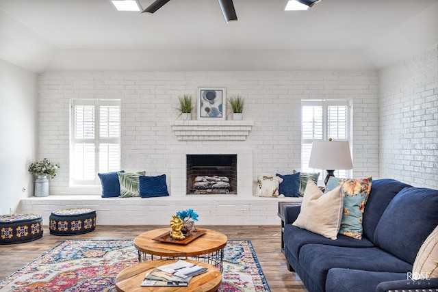 living room featuring lofted ceiling, brick wall, and a brick fireplace