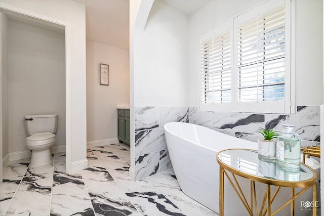 bathroom featuring vanity, toilet, tile walls, and a tub to relax in